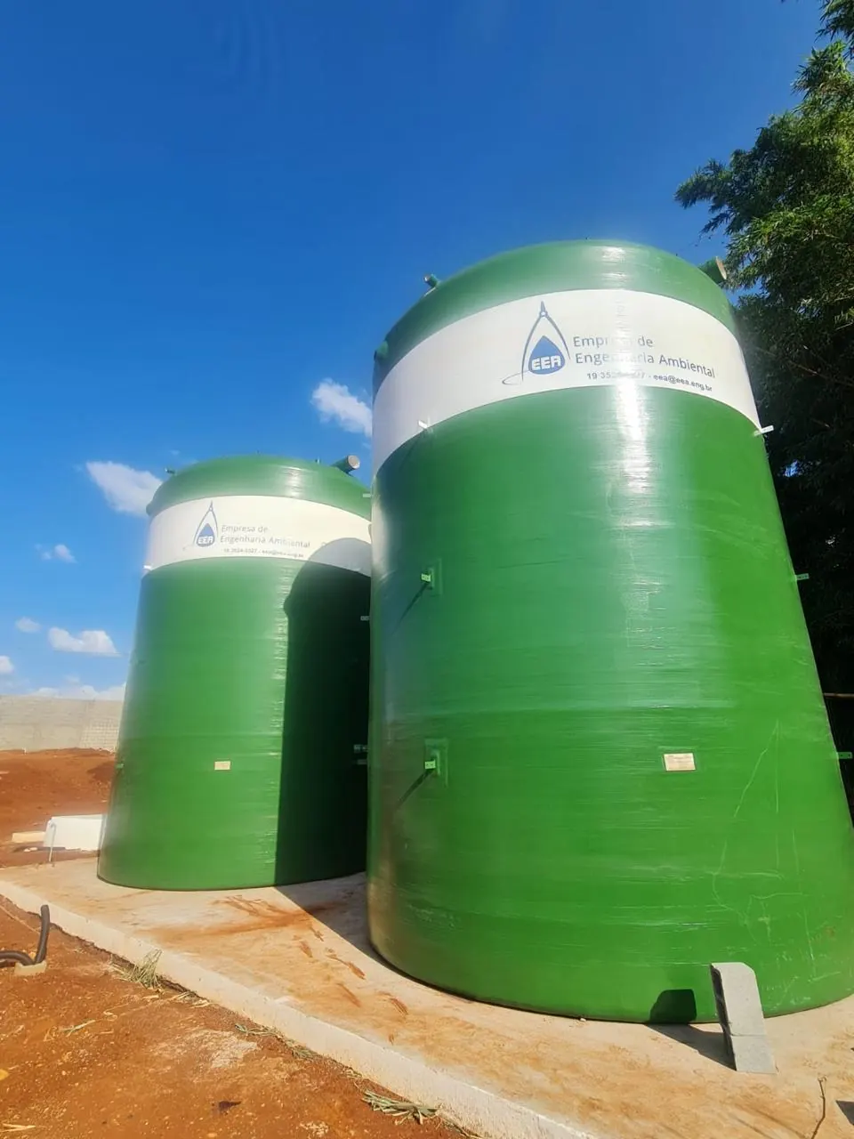 Dois reservatórios verticais em PRFV, verdes, instalados sobre base de concreto